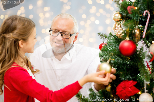 Image of grandfather and granddaughter at christmas tree