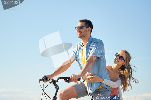 Image of happy couple riding bicycle together in summer