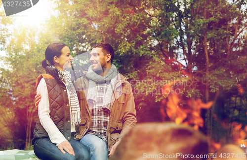 Image of happy couple sitting on bench near camp fire