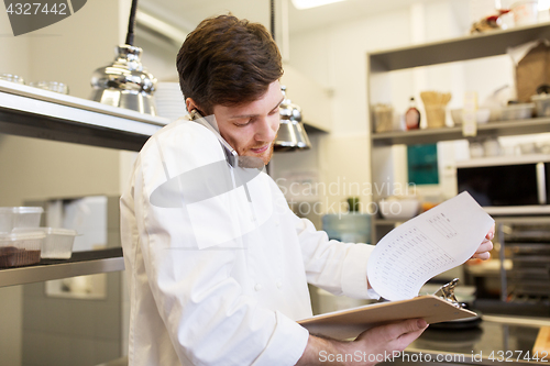 Image of chef cook calling on smartphone at restaurant kitchen