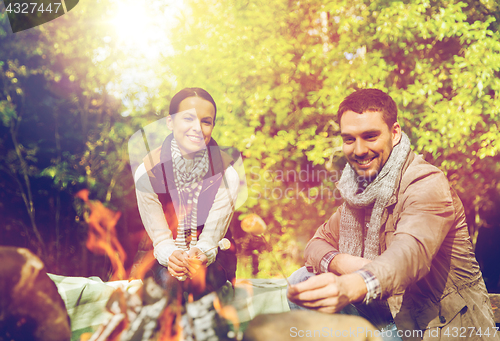 Image of happy couple roasting marshmallow over camp fire