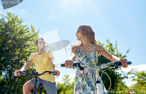 Image of happy young couple riding bicycles in summer