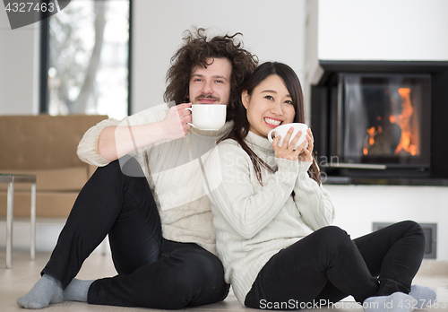 Image of happy multiethnic couple  in front of fireplace