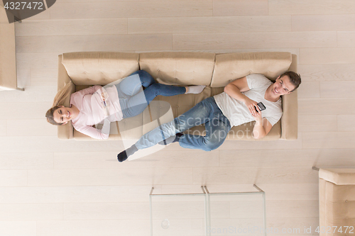 Image of Young couple on the sofa watching television top view