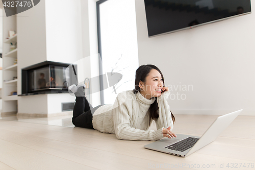 Image of young Asian woman using laptop on the floor