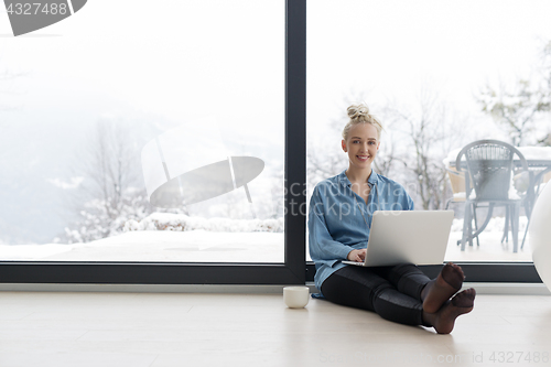 Image of woman drinking coffee and using laptop at home