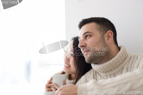 Image of multiethnic couple enjoying morning coffee by the window