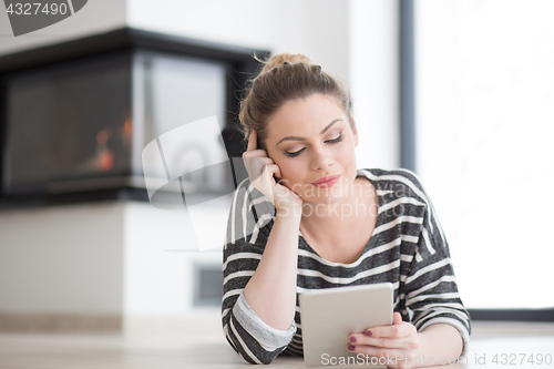 Image of woman using tablet computer in front of fireplace
