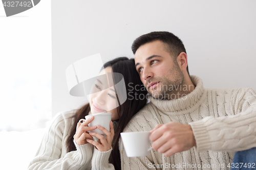 Image of multiethnic couple enjoying morning coffee by the window