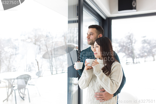 Image of multiethnic couple enjoying morning coffee by the window