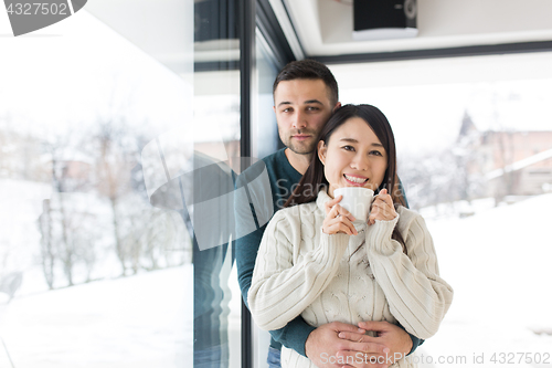 Image of multiethnic couple enjoying morning coffee by the window