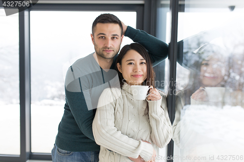 Image of multiethnic couple enjoying morning coffee by the window