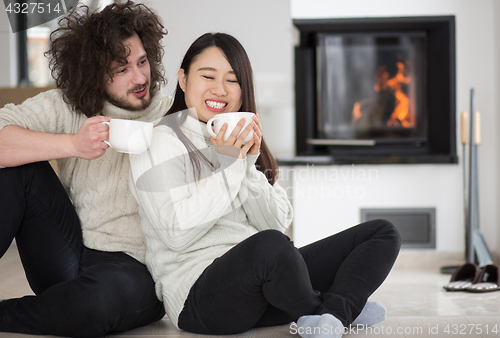 Image of happy multiethnic couple  in front of fireplace