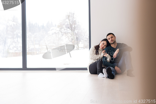 Image of multiethnic couple sitting on the floor near window at home