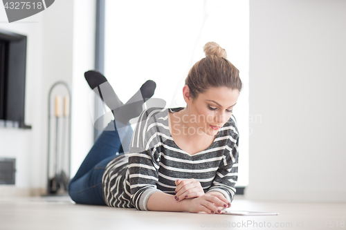 Image of woman using tablet computer in front of fireplace