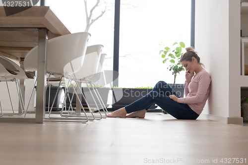 Image of young woman using mobile phone on the floor