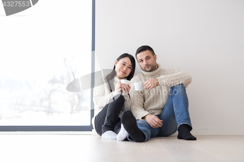 Image of multiethnic couple enjoying morning coffee by the window