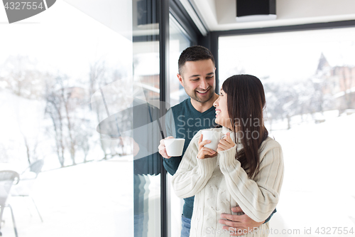 Image of multiethnic couple enjoying morning coffee by the window