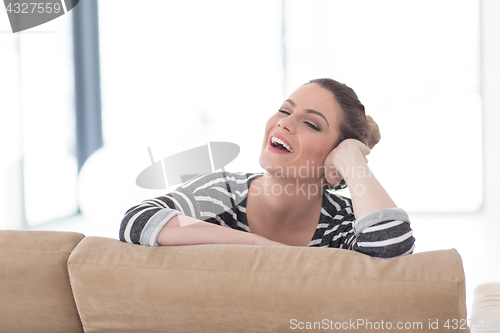 Image of portrait of a young beautiful woman sitting on the sofa