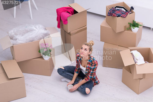 Image of woman with many cardboard boxes sitting on floor