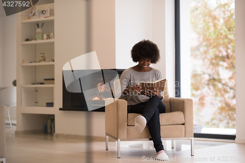 Image of black woman at home reading book