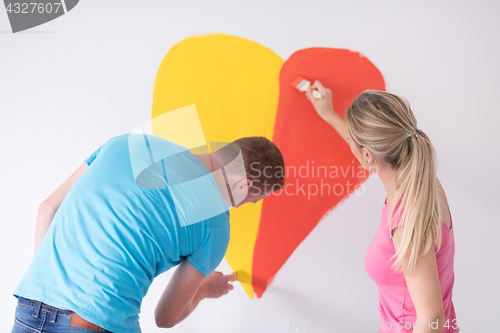 Image of couple are painting a heart on the wall