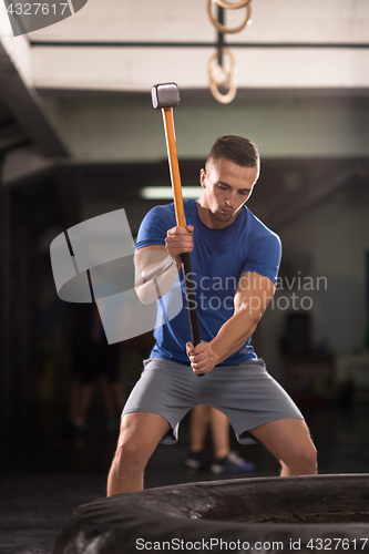 Image of man workout with hammer and tractor tire