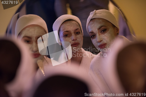 Image of women putting face masks in the bathroom