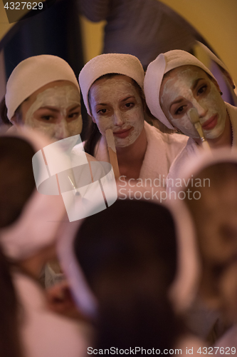 Image of women putting face masks in the bathroom