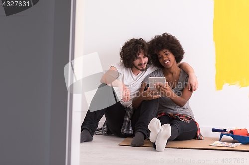 Image of young multiethnic couple relaxing after painting