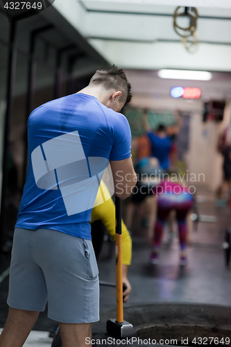 Image of man workout with hammer and tractor tire