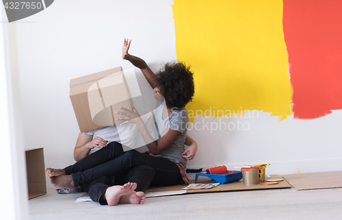 Image of young multiethnic couple playing with cardboard boxes