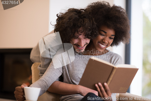 Image of multiethnic couple hugging in front of fireplace