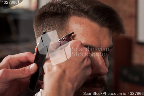 Image of The hands of barber making haircut to young man in barbershop