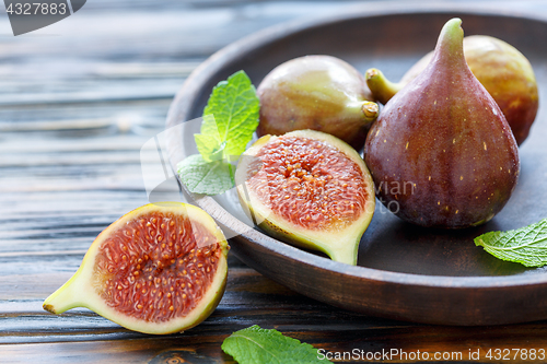 Image of Fresh figs and mint leaves on a wooden dish.