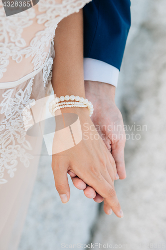 Image of The groom gently holds the bride by the hand