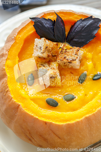 Image of Pumpkin soup with croutons and purple basil closeup.