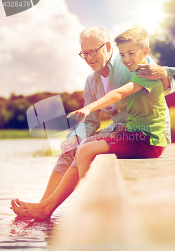 Image of grandfather and grandson sitting on river berth