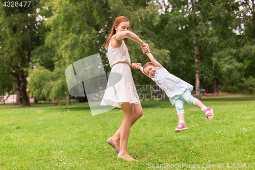 Image of happy mother playing with baby girl at summer park