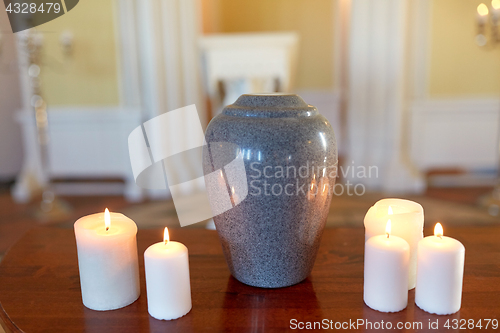 Image of cremation urn and candles burning in church