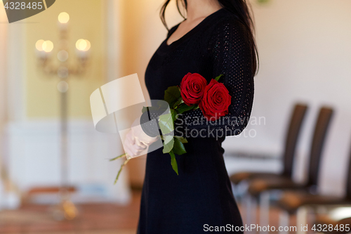 Image of woman with red roses at funeral in church