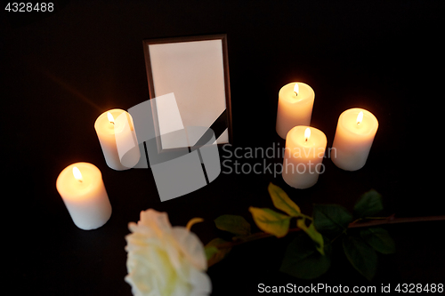 Image of photo frame with black ribbon, flower and candles