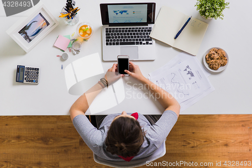Image of woman with smartphone and laptop at office table