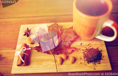 Image of cup of tea, maple leaf and almond on wooden board