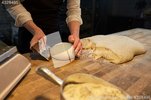 Image of baker portioning dough with bench cutter at bakery