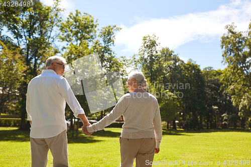 Image of happy senior couple walking at summer park