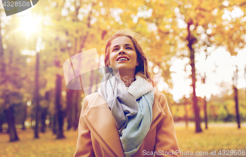 Image of beautiful happy young woman walking in autumn park
