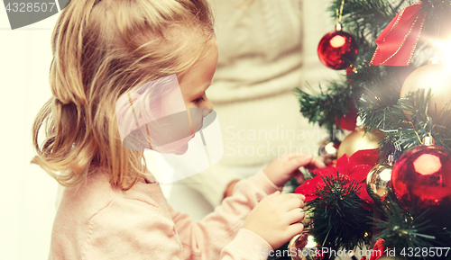 Image of little girl decorating christmas tree at home