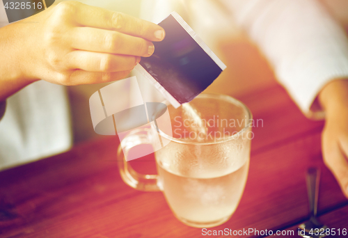 Image of woman pouring medication into cup of water