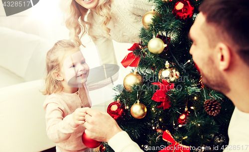 Image of happy family decorating christmas tree at home